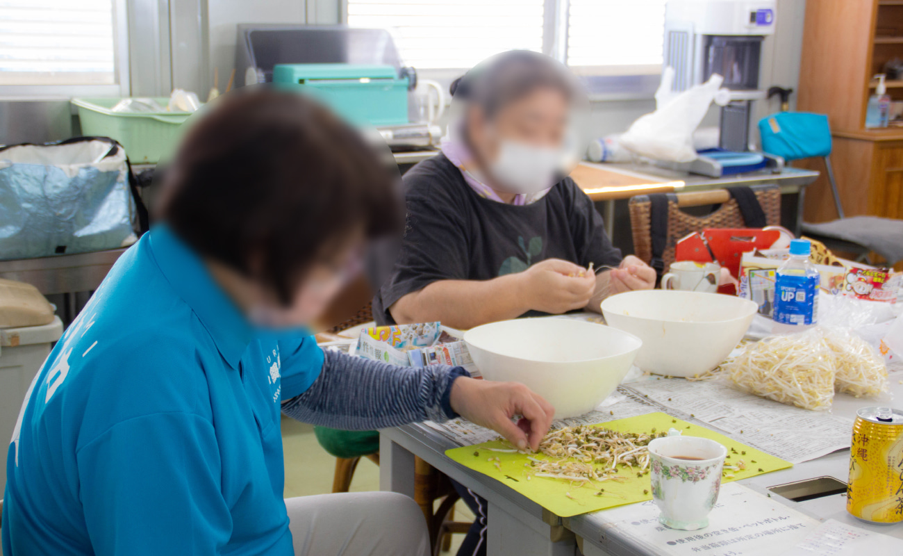 moyashi-2 ホープうるまの建物の中で利用者が野菜の袋詰め作業をしている様子