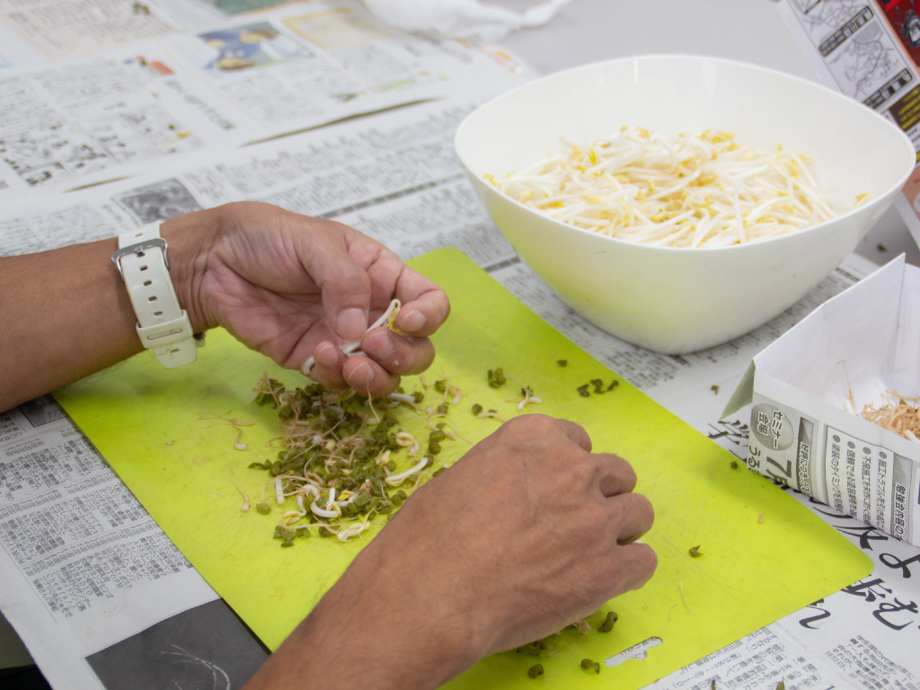 ホープうるまの建物の中で利用者が野菜の袋詰め作業をしている様子